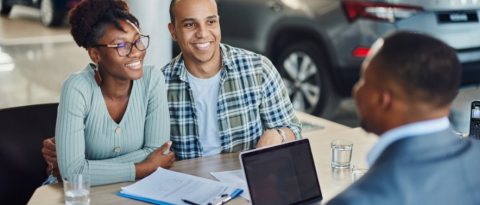 Two co-buyers discussing their auto financing with a GM dealership salesperson. 