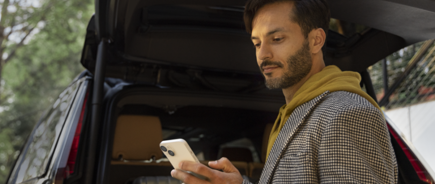 Man outside SUV accessing MyAccount from his smartphone. 